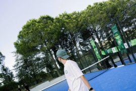 Mavi padel kortunda raketiyle oyuna hazırlanan sporcu.