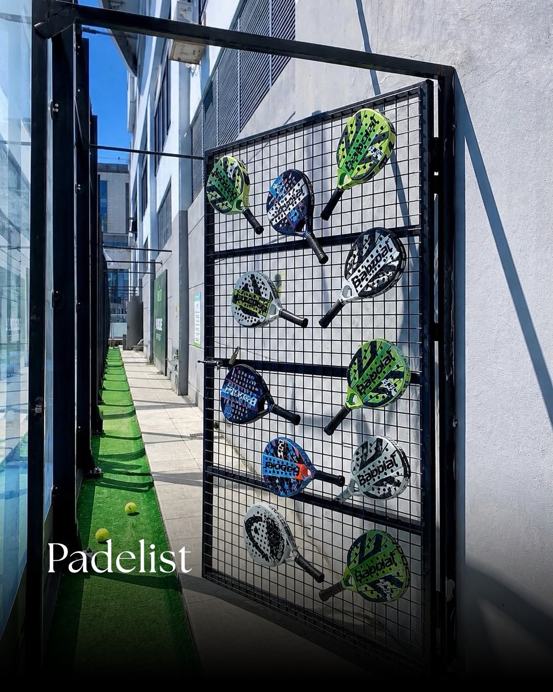Padelist’te duvara asılmış farklı renklerde padel raketleri.
